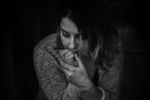 sad woman with hands in mouth