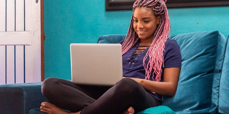 sober woman on couch typing on lap top looking for online sobriety support