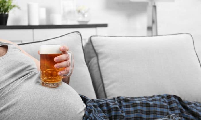 man with beery belly on couch holding beer