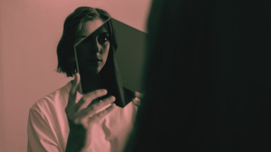 A woman examines her shadow through a transparent shape