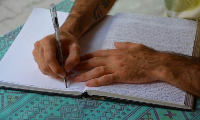 person writing in journal with shadow work prompts