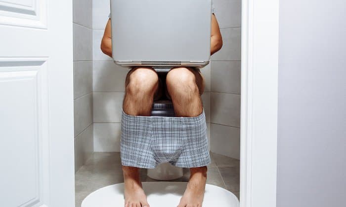 man sitting on toilet having diarrhea after drinking
