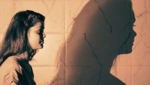A profile of a woman and her shadow projected on the wall representing her shadow archetype
