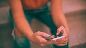 A woman with ripped jeans sits on the couch and drunk texts