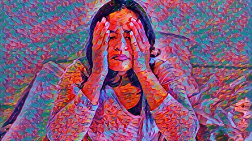 A woman sits with her head in her hands looking distraught
