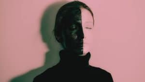 A woman in a black turtle neck with her face painted half in black and half in white symbolizing BPD splitting
