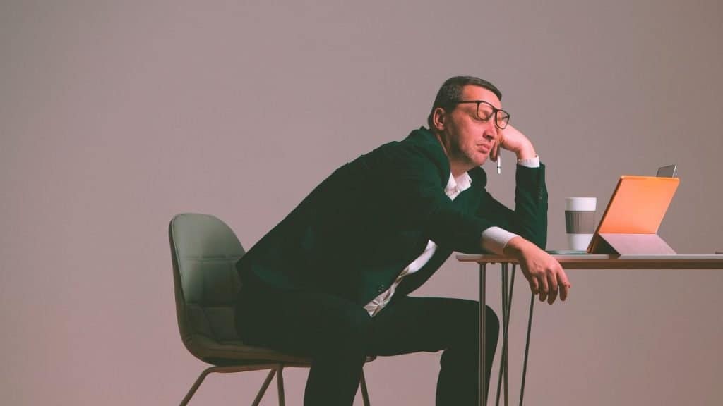 Sober man is bored and rests head on his hand at his desk