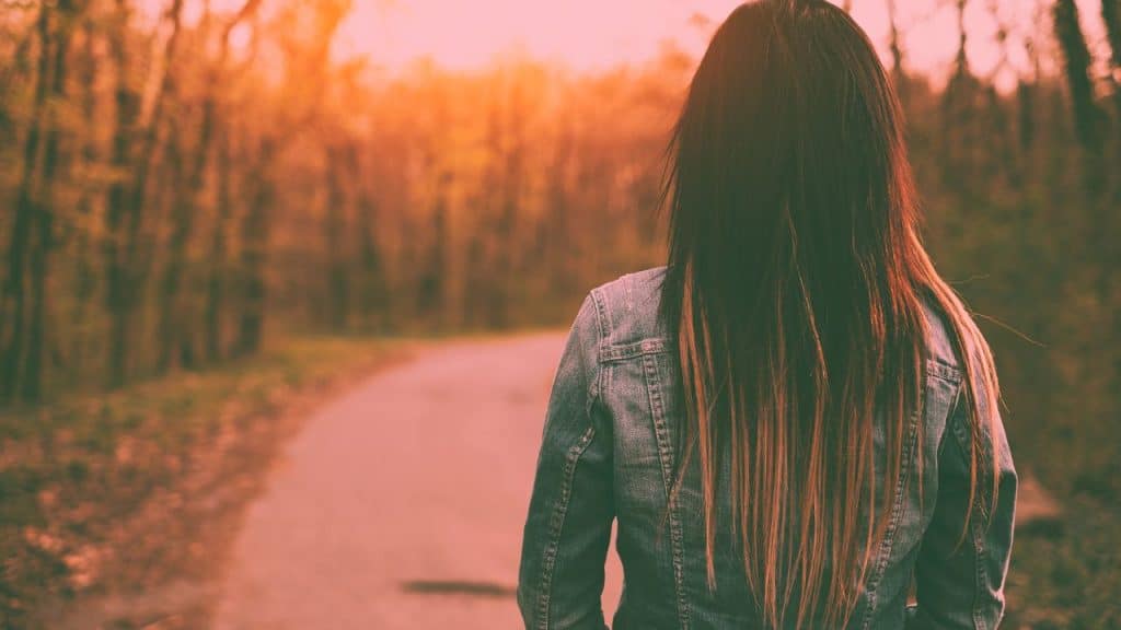 An woman with an avoidant attachment style turns her back to the camera and stairs at an empty road