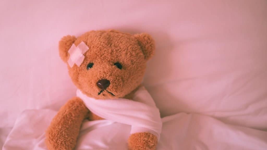 A teddy bear with bandages looking sad