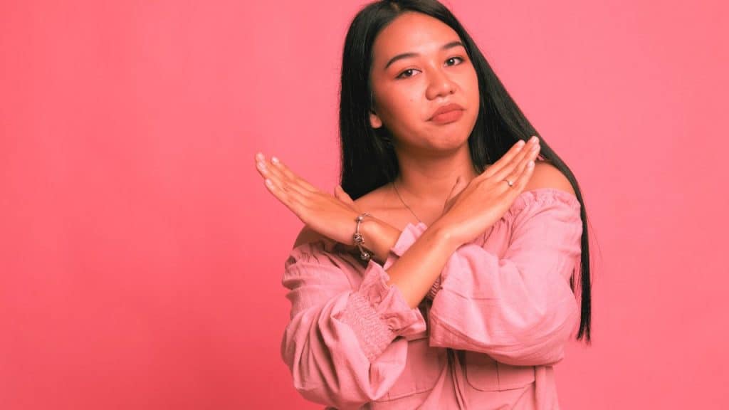A woman crosses her hands in a "no" gesture signaling that she is saying no to her gaslighter