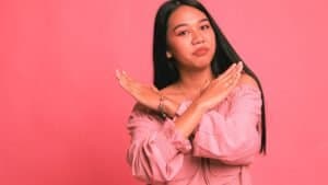 A woman crosses her hands in a "no" gesture signaling that she is saying no to her gaslighter