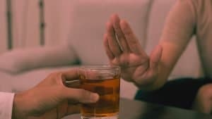 A hand rejects a glass of alcohol