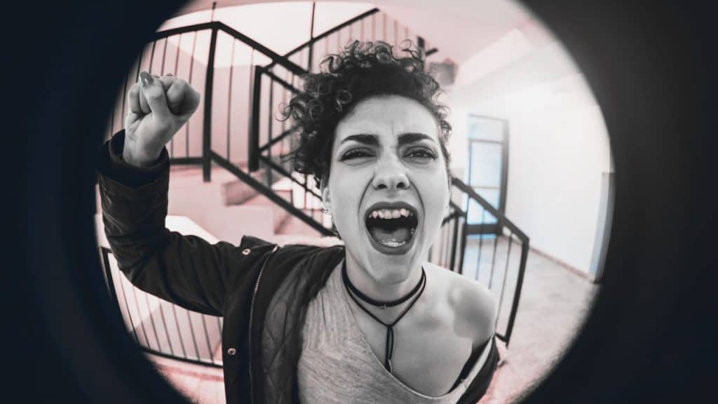 An angry drunk woman pounds on the door. We see her through the keyhole