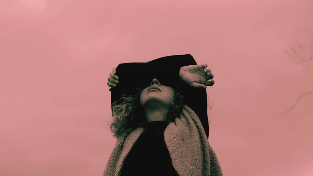 A woman struggling with PAWS folders her arms over her eyes