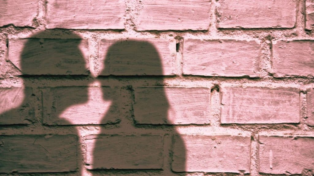 Two shadows of a couple against a brick wall