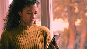 A woman stares down at her phone in disbelief, ignored by her BPD partner