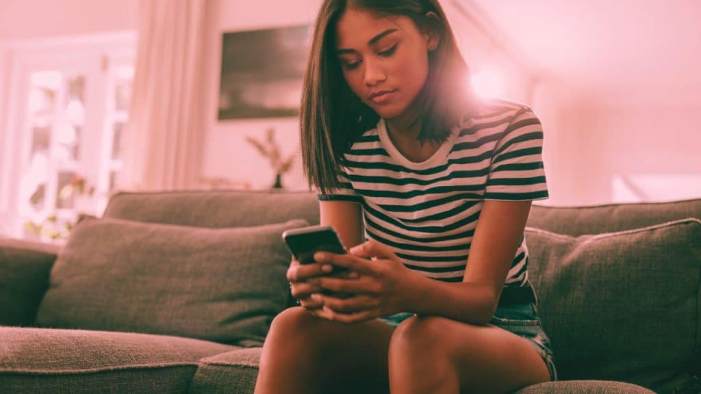 A woman stares down at her phone wondering if she's being ignored or ghosted