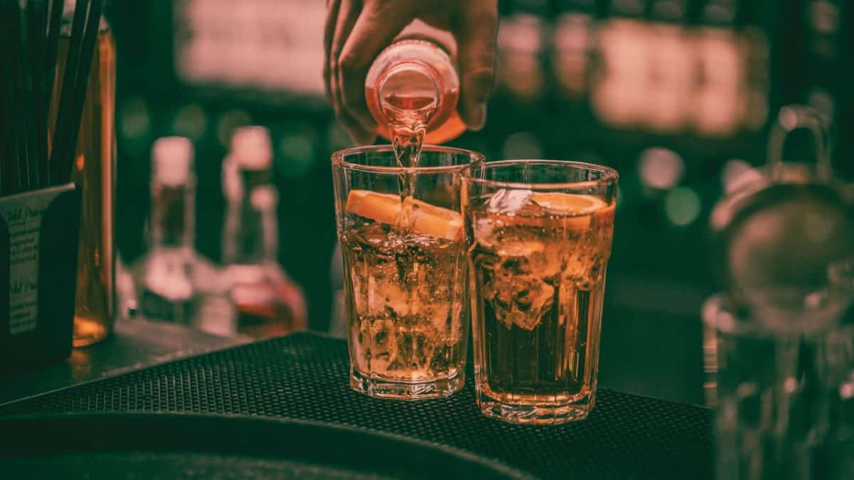 Someone pours liquor into a glass on a bar