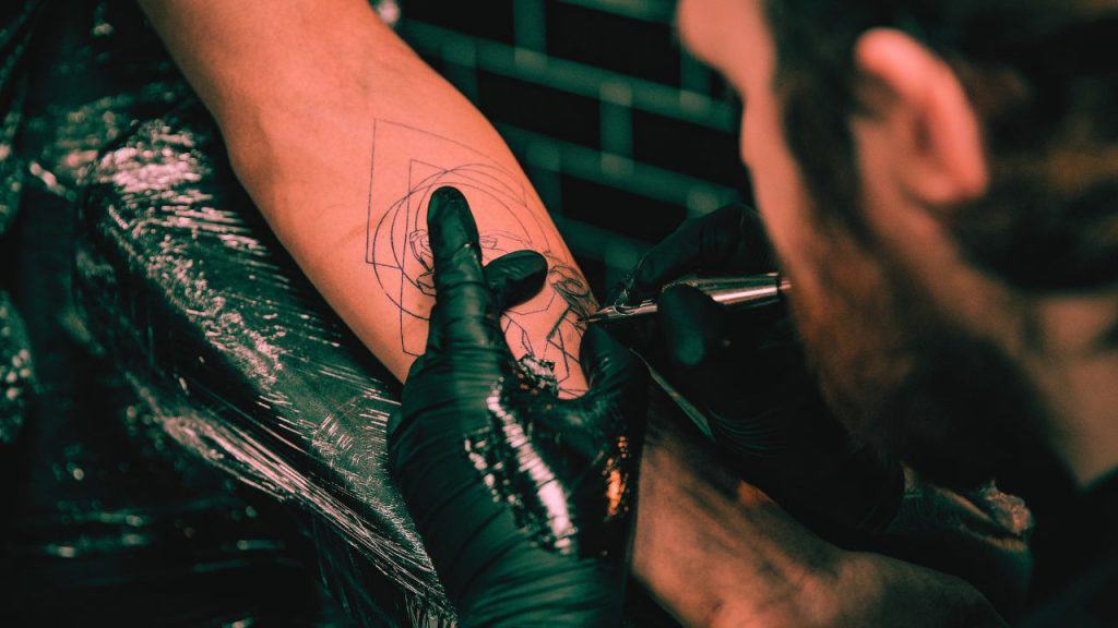 A tattoo artist works on a tattoo for a client
